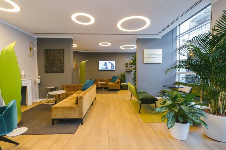 Bürointerieur mit Sofas, Pflanzen und moderner Beleuchtung.